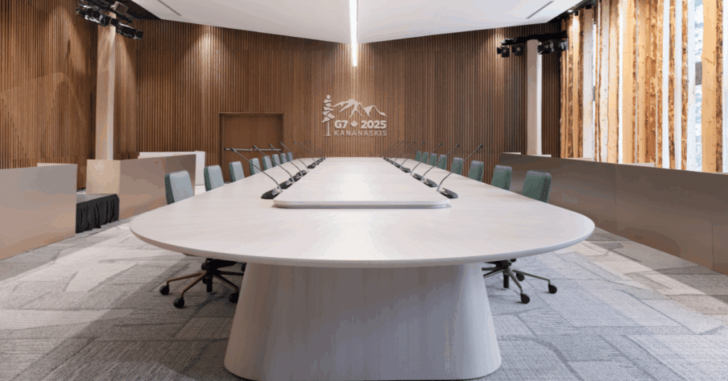 Empty G7 Summit conference room in Kananaskis with round table, microphones, and modern wood-panelled walls